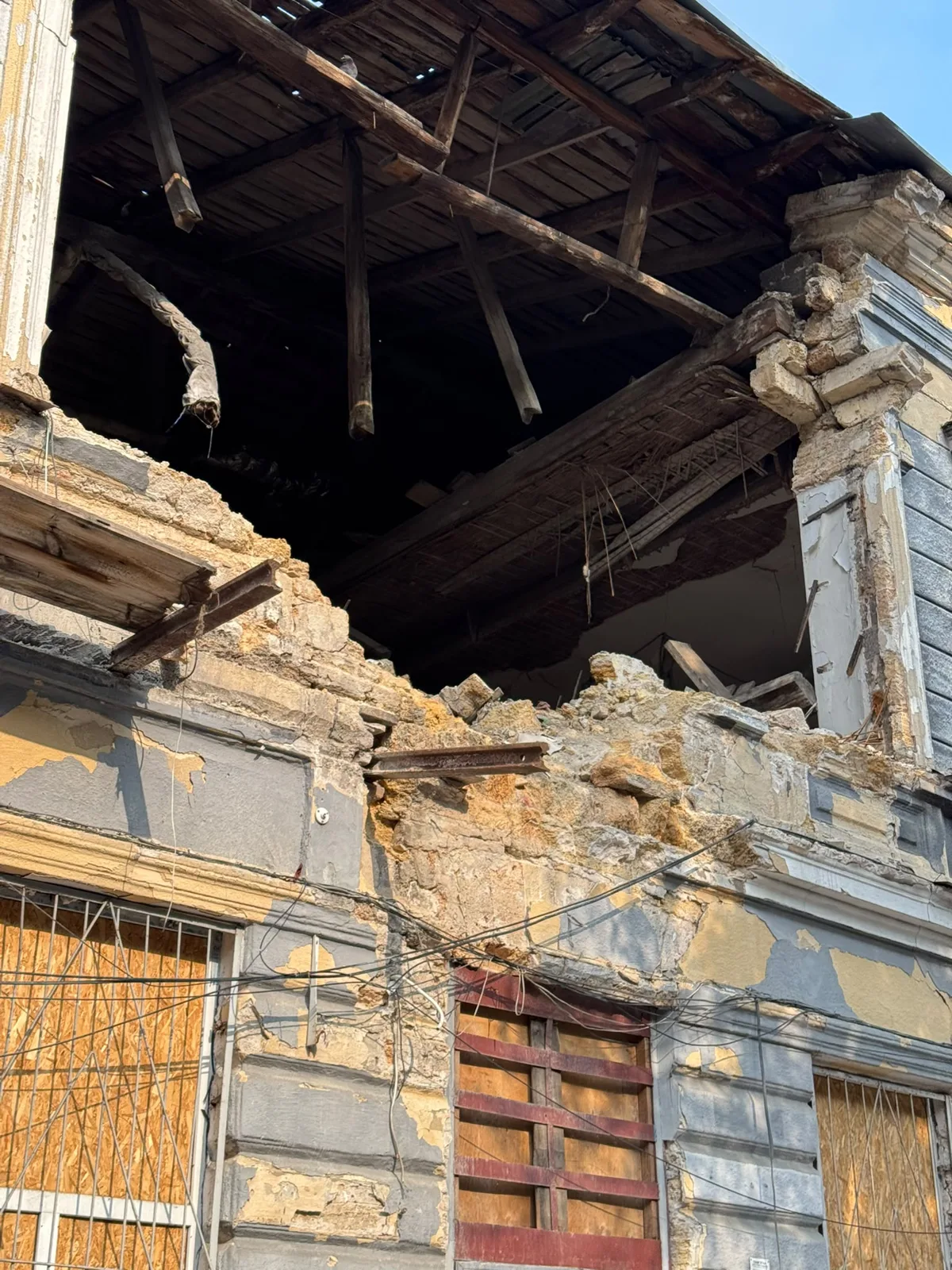 Altbaufassade mit eingestürzter Decke und verbretterten Fenstern
