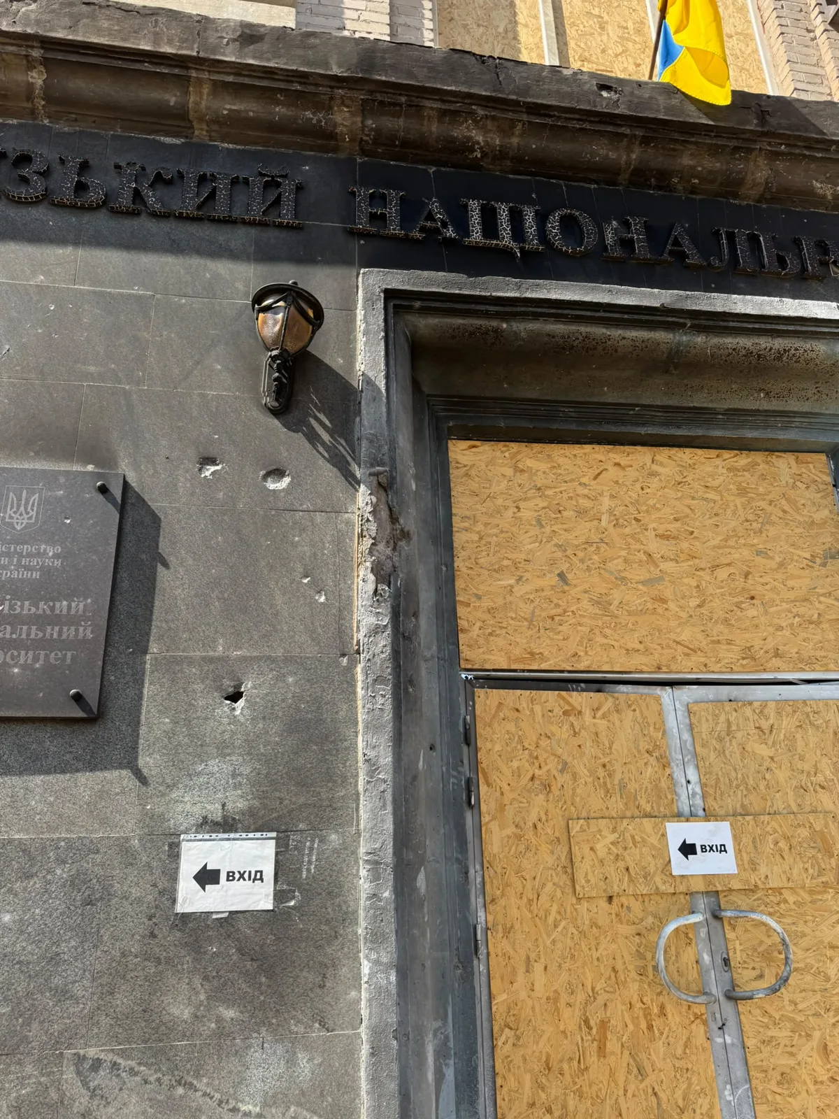 Beschädigte Fassade und mit Holz verschlossene Tür einer Universität
